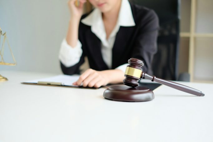 Employment Law Woman in a suit contemplating while seated at a desk with a gavel nearby.